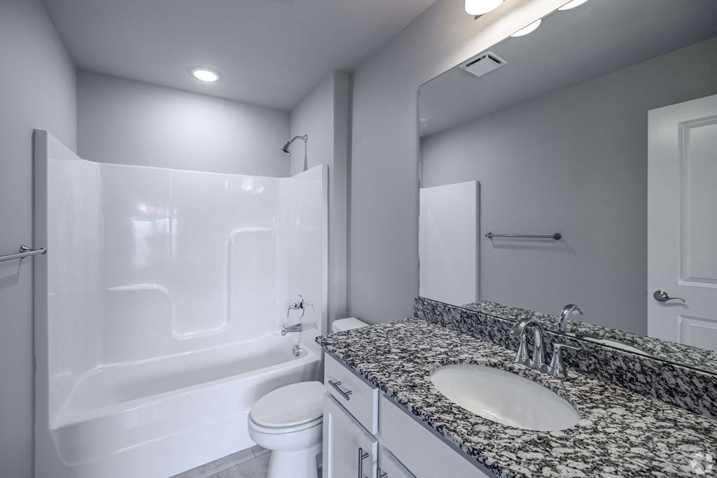 A white bathroom with a marble countertop and a white toilet.