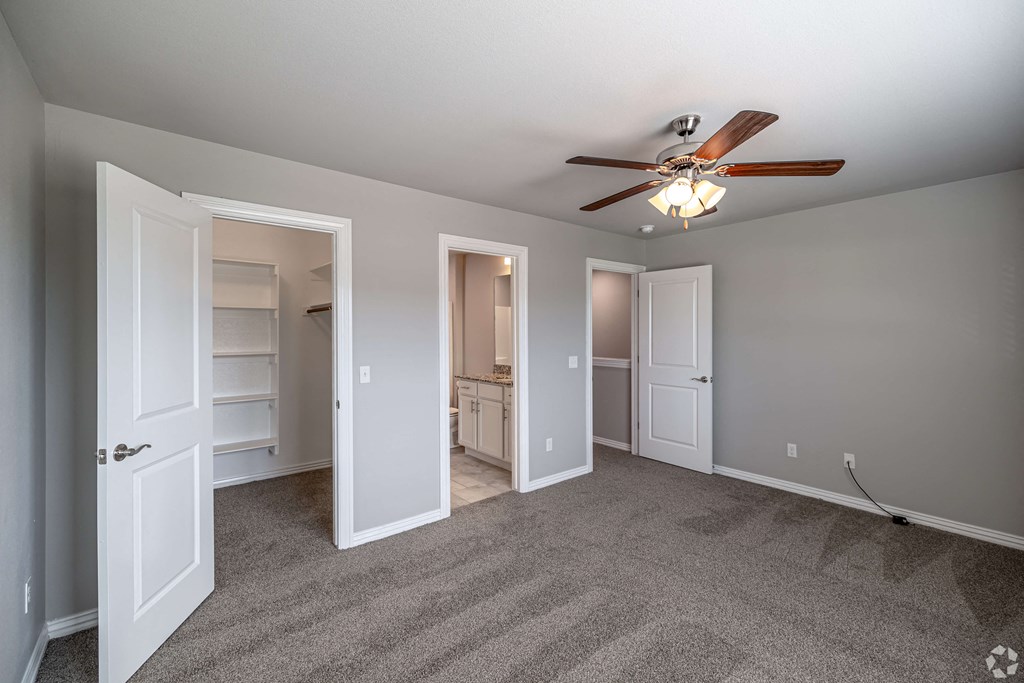 A room with a ceiling fan and carpeted floor.