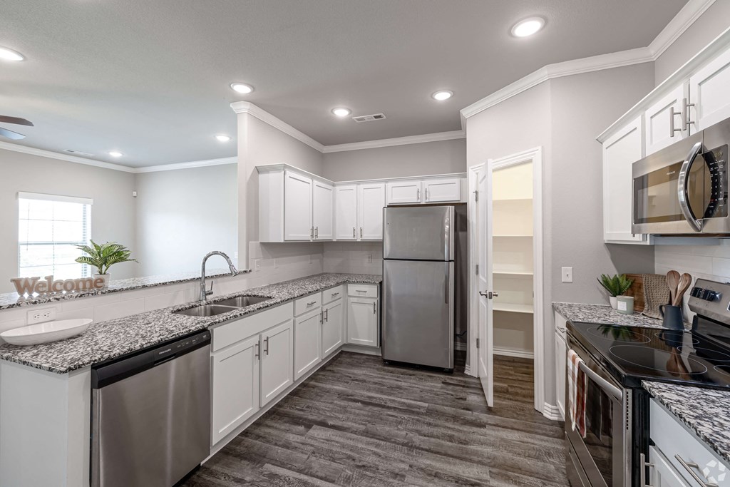 A kitchen with a stainless steel refrigerator and black countertops.