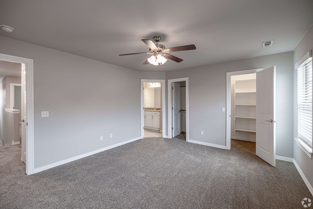 A spacious room with a ceiling fan and carpeted floor.