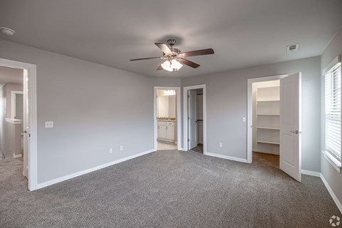 A spacious room with a ceiling fan and carpeted floor.
