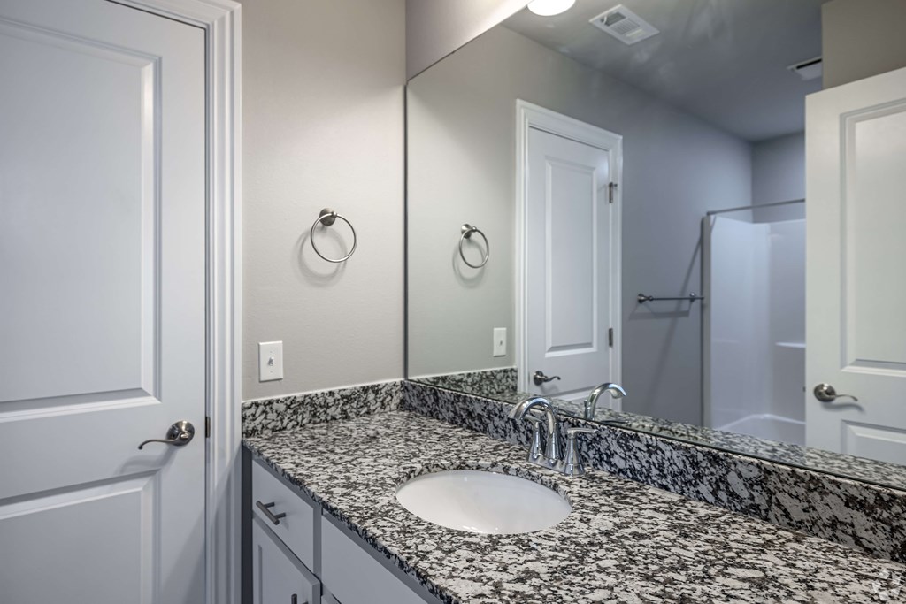 A bathroom with a marble countertop and a white sink.