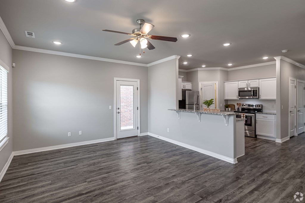 A spacious kitchen and living room with a ceiling fan and recessed lighting.