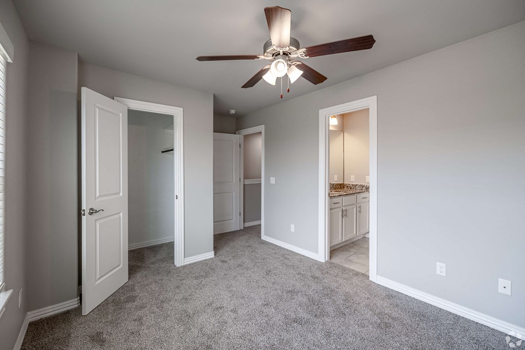 A room with a ceiling fan and carpeted floor.
