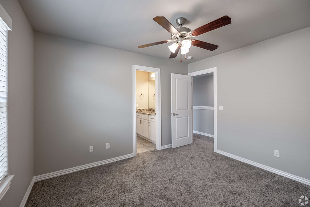 A room with a ceiling fan and carpeted floor.