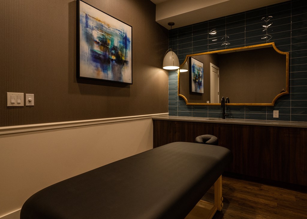 a massage table in a room with a mirror  at The Clearing at ONE28, Olathe, KS, 66062