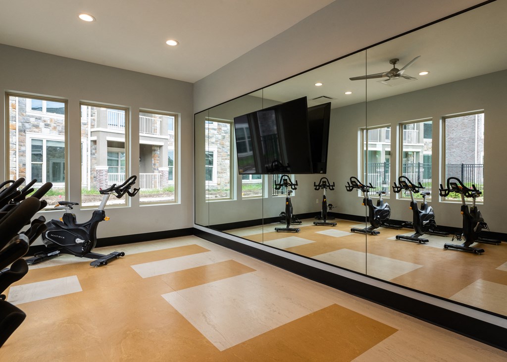 the gym has a large mirror and a slew of exercise equipment  at The Clearing at ONE28, Olathe, Kansas