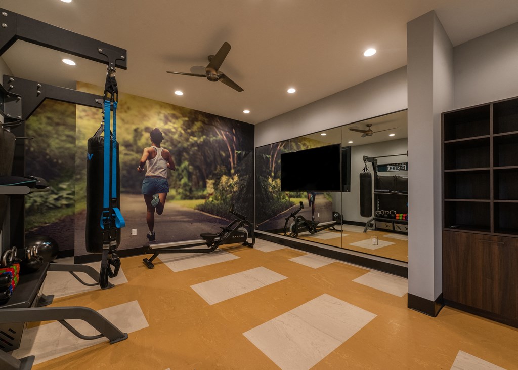 a home gym with a wall mural of a man running on a treadmill  at The Clearing at ONE28, Olathe, 66062