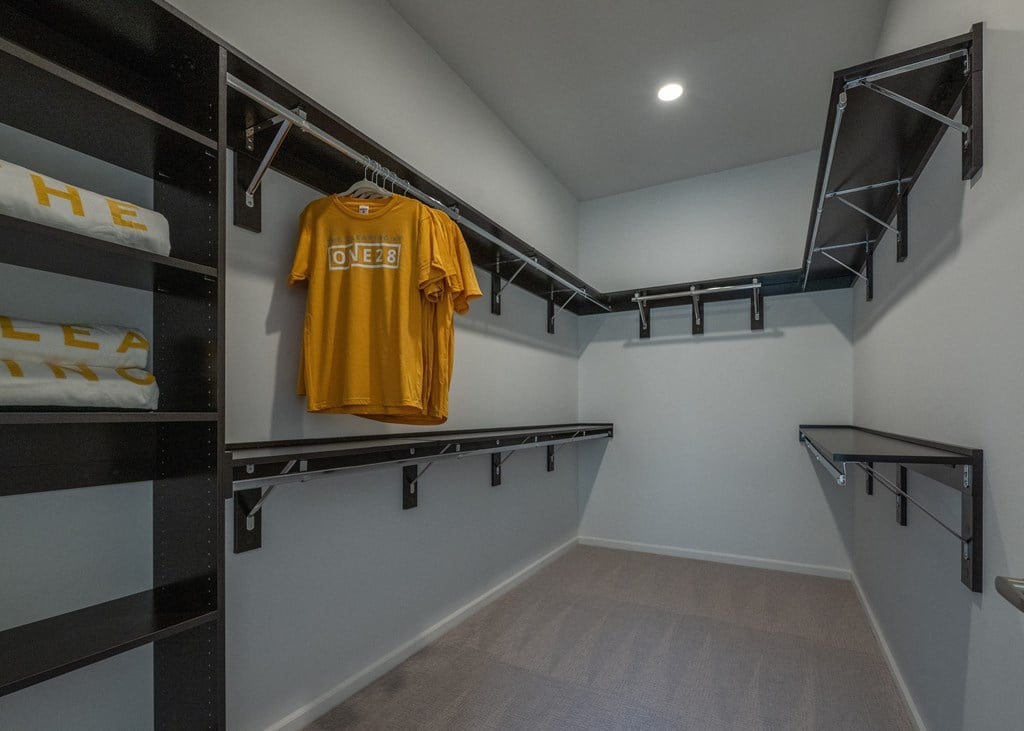 a walk in closet with a yellow shirt hanging on the wall and a black closet  at The Clearing at ONE28, Olathe, Kansas