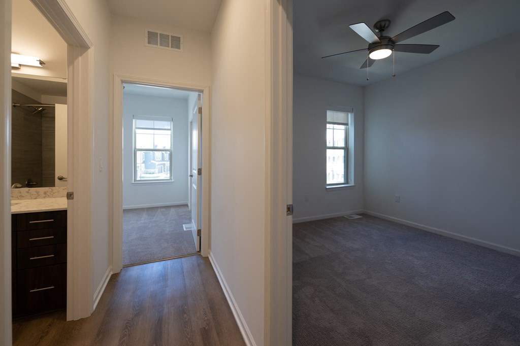 an empty living room with a ceiling fan and a bathroom