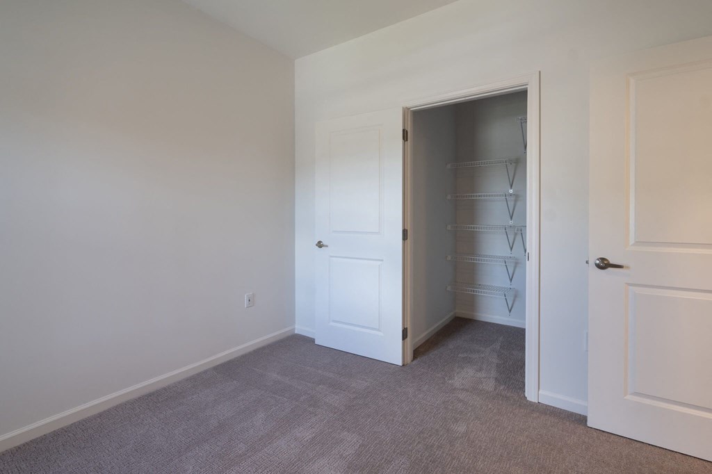 a room with white walls and a closet and a door to a closet