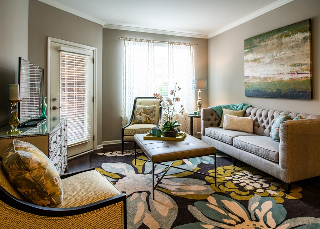 A living room with a couch, chair, and a painting on the wall.