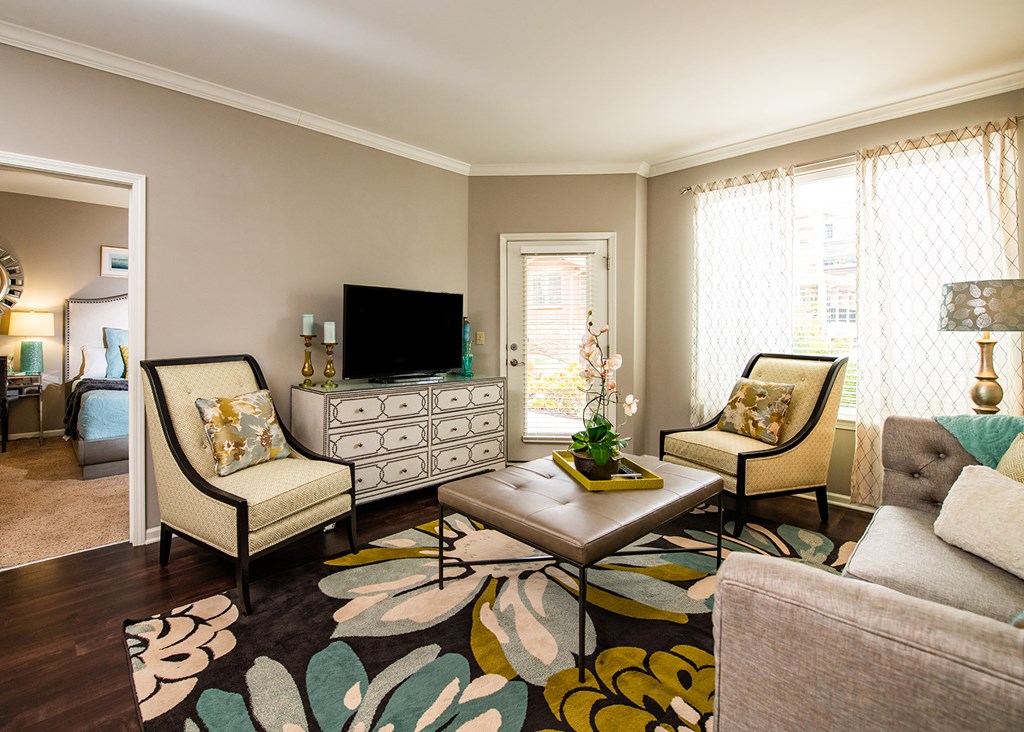 A living room with a sofa, two chairs, a coffee table, and a TV.