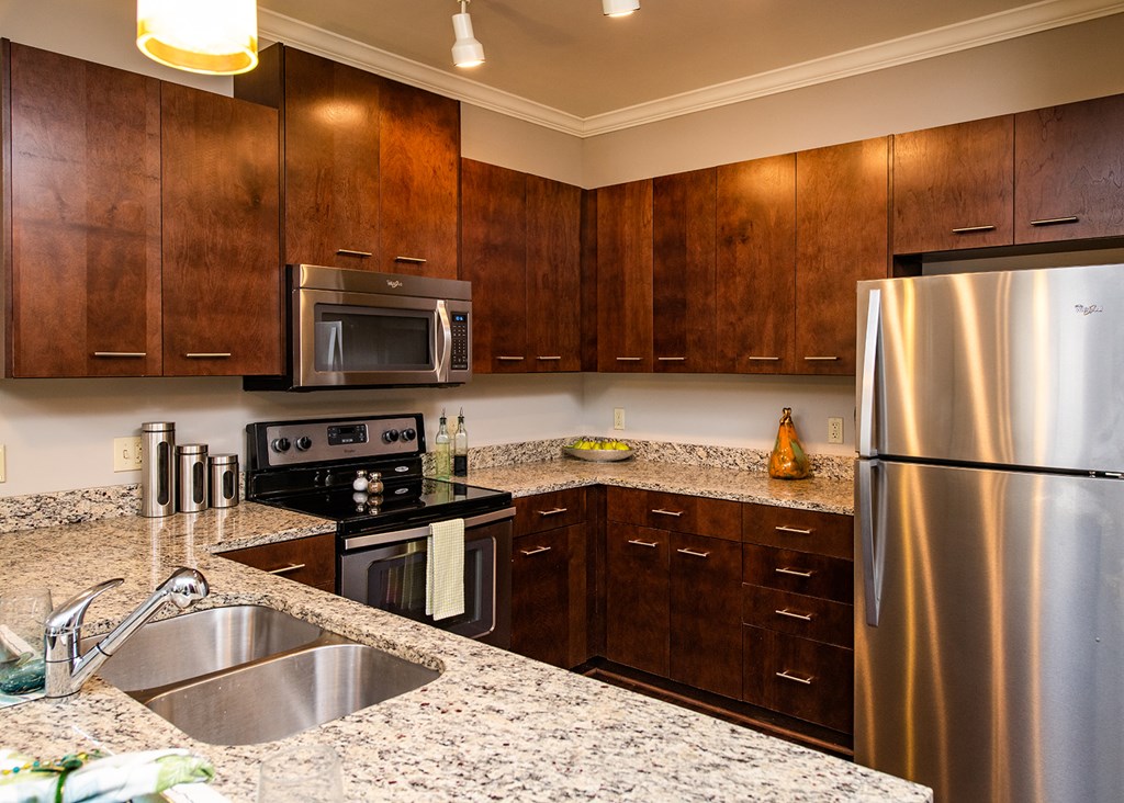 A kitchen with a stainless steel refrigerator and wooden cabinets.