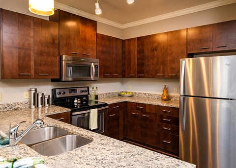 A kitchen with a stainless steel refrigerator and wooden cabinets.