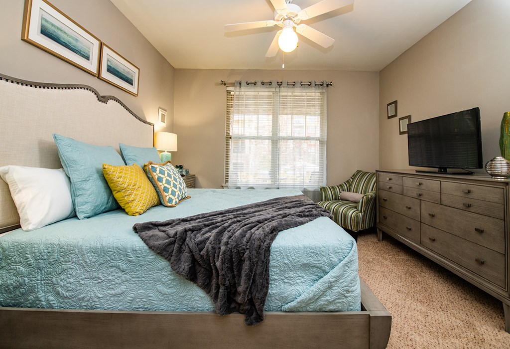 A bedroom with a bed, dresser, and ceiling fan.