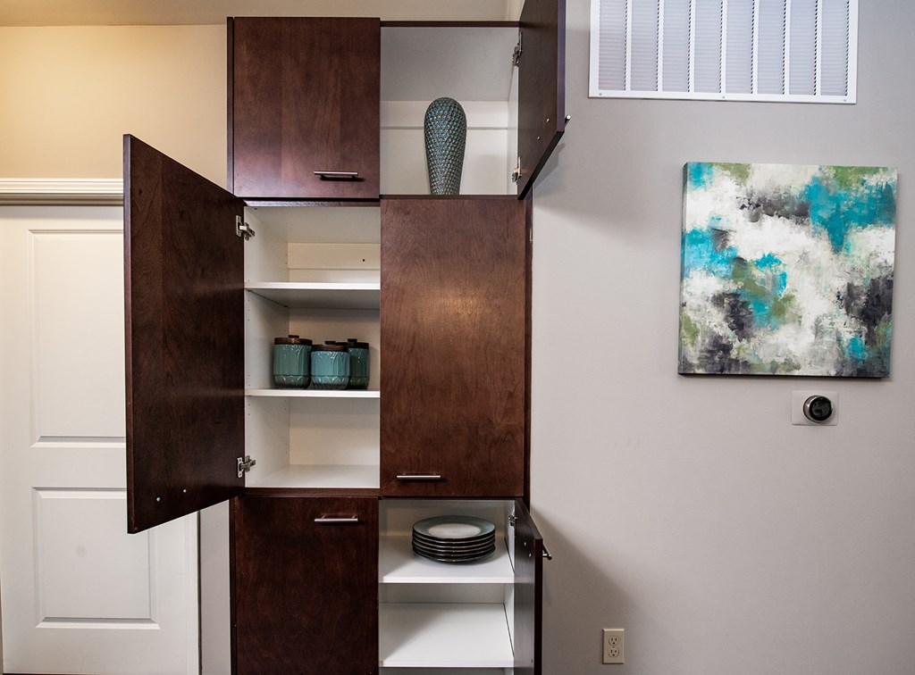 A brown cabinet with a white interior is open, revealing plates and bowls.