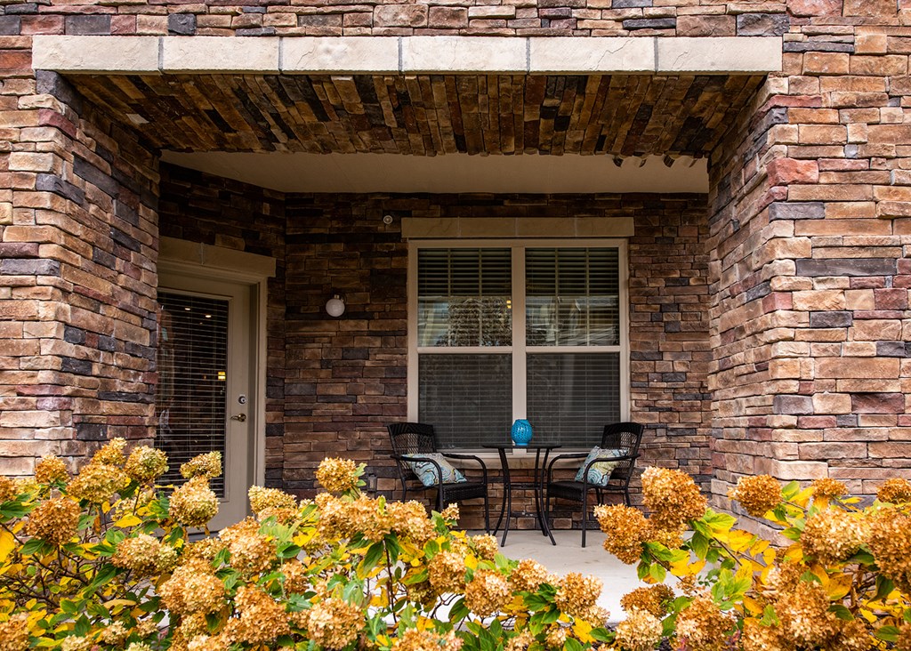 A patio with a table and chairs is framed by a brick wall.