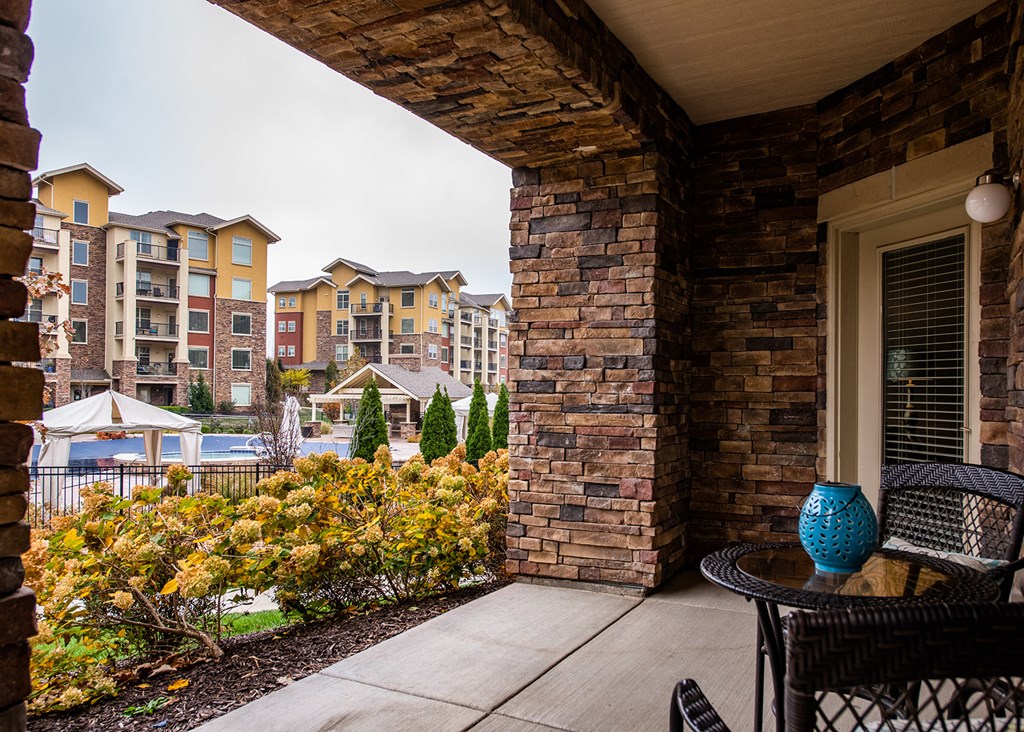 A balcony with a table and chairs overlooking apartment buildings.