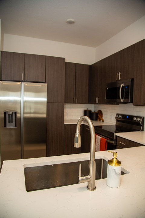 A kitchen with a stainless steel refrigerator and a black microwave above the stove.