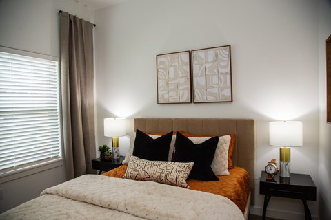 A bedroom with a large bed and two lamps.