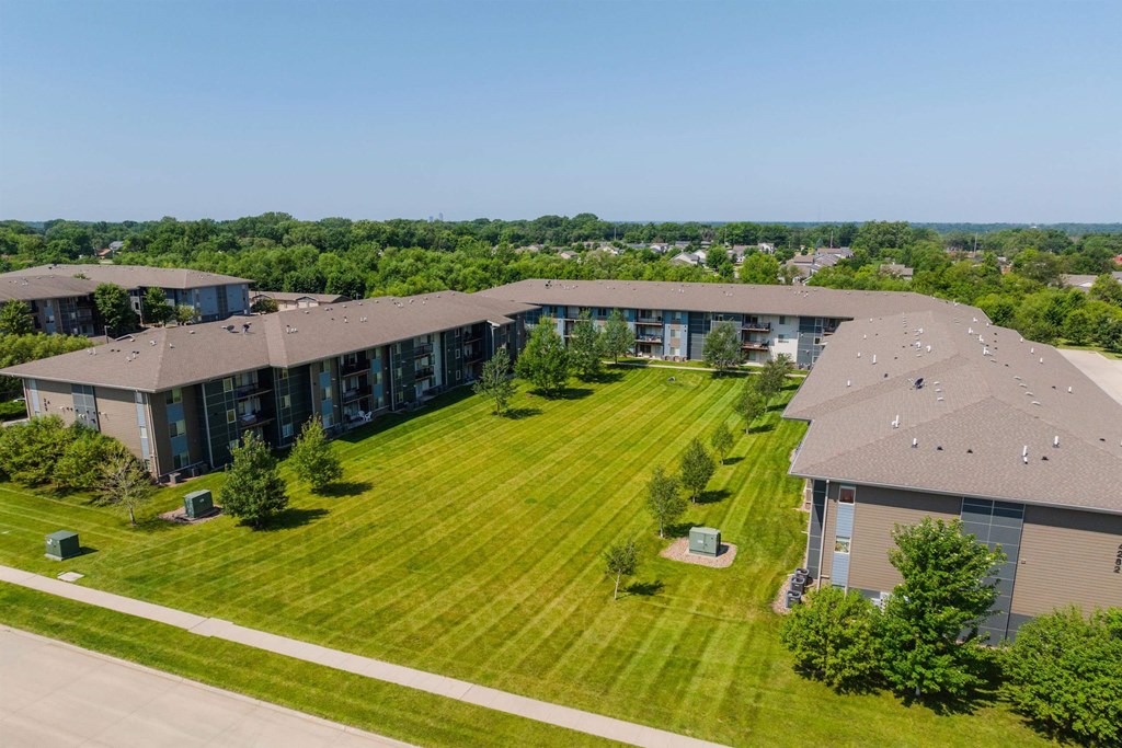 A large, modern building with a spacious lawn in front.