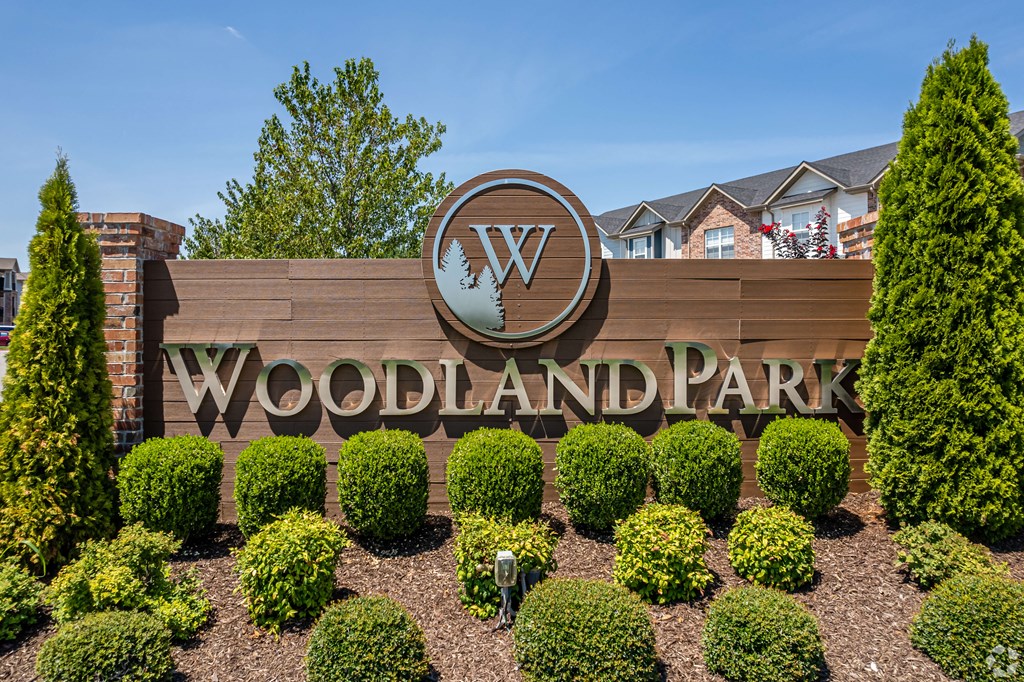a sign for the woodland park sign in front of a garden