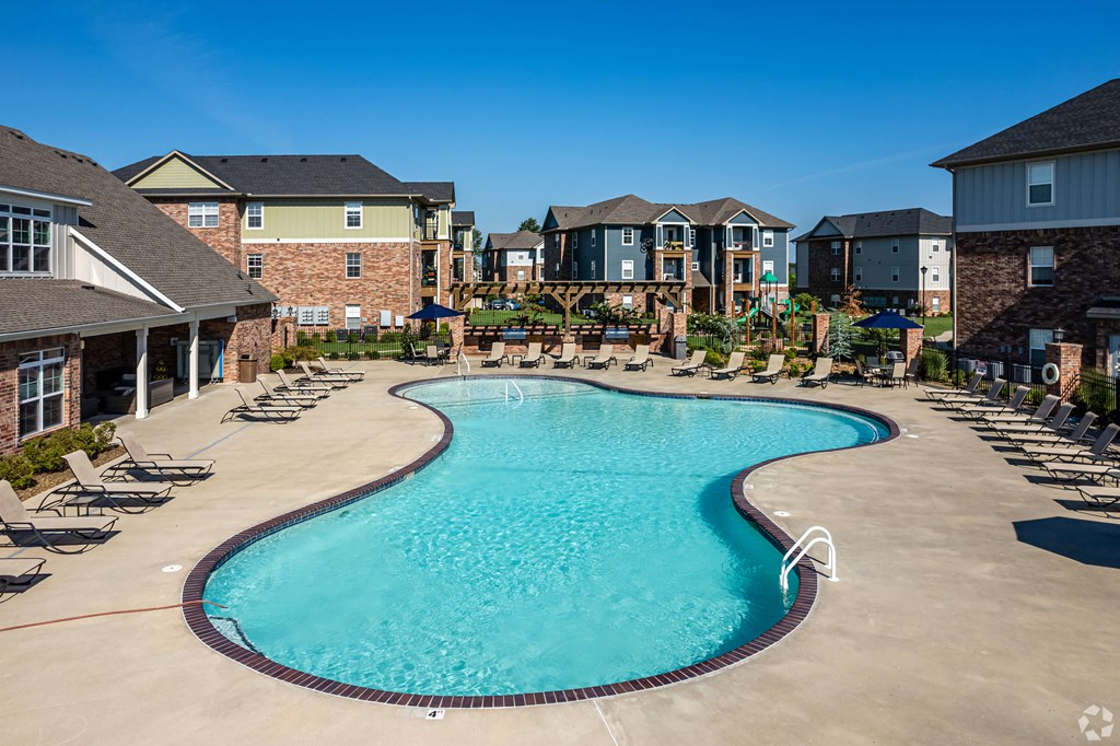 a large swimming pool with chairs in front of apartment buildings