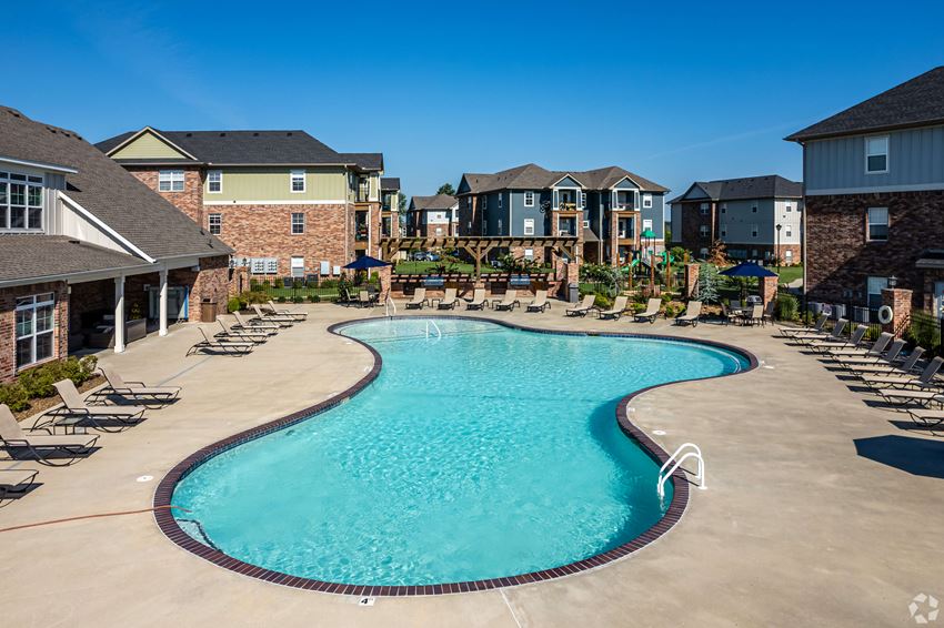 a large swimming pool with chairs in front of apartment buildings