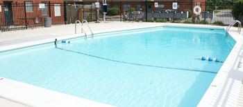 A large swimming pool with a diving board and no one in it.