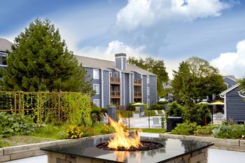 A fire burns in a fire pit in a backyard.