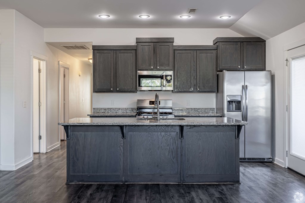 A kitchen with black cabinets and a stainless steel refrigerator.