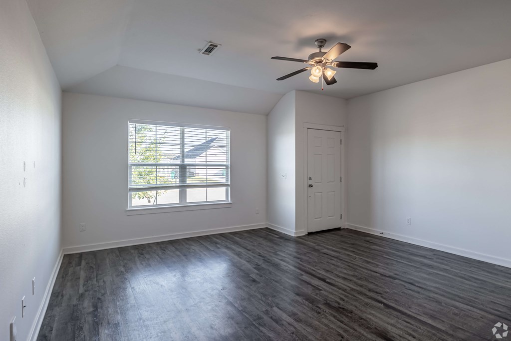 A room with a ceiling fan and a window with blinds.