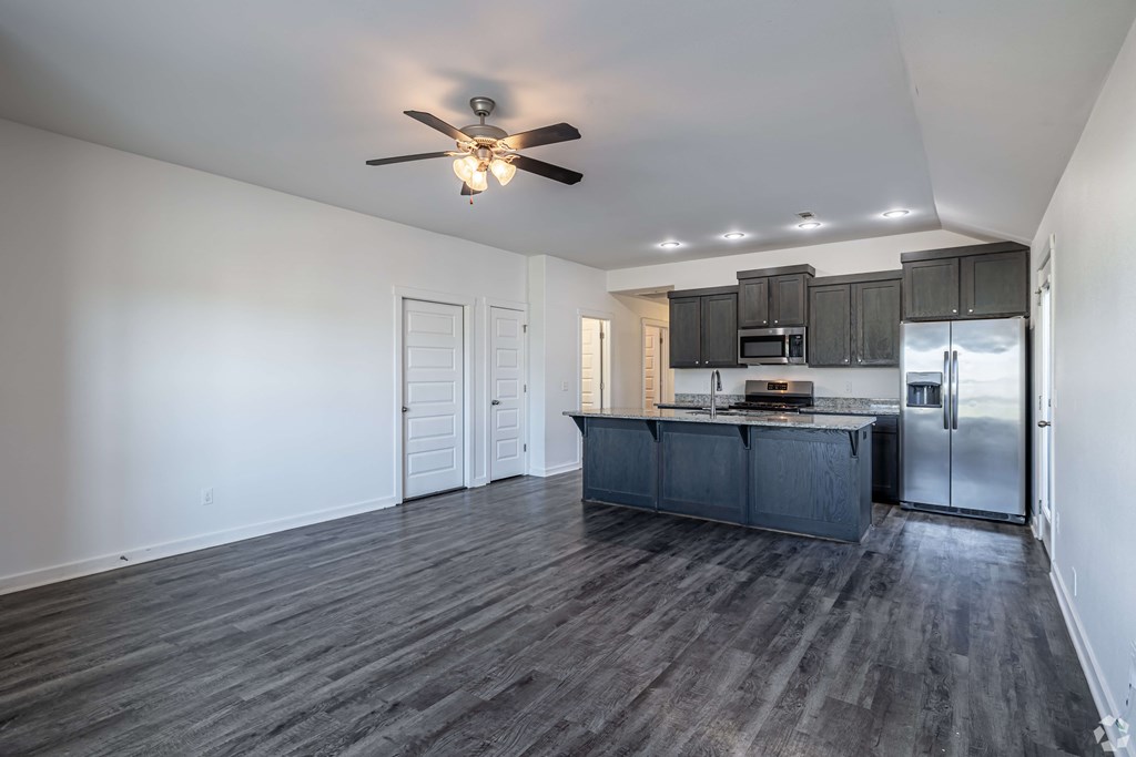 A spacious kitchen with dark wood floors and white walls.