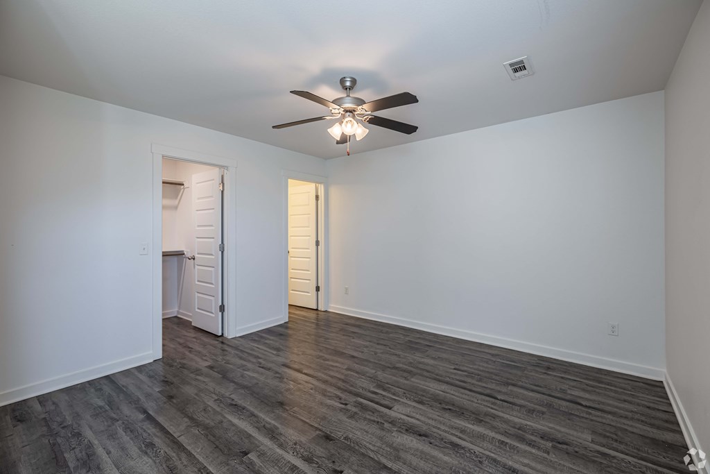 A room with a ceiling fan and wooden flooring.