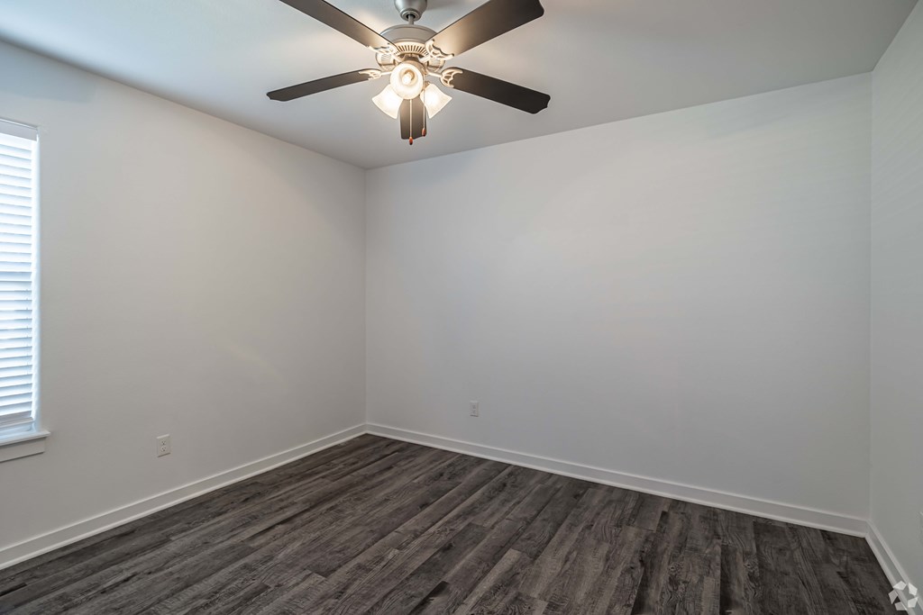 A room with a ceiling fan and wooden flooring.