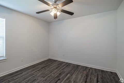 A room with a ceiling fan and wooden flooring.