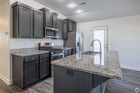 A kitchen with black cabinets and granite countertops.
