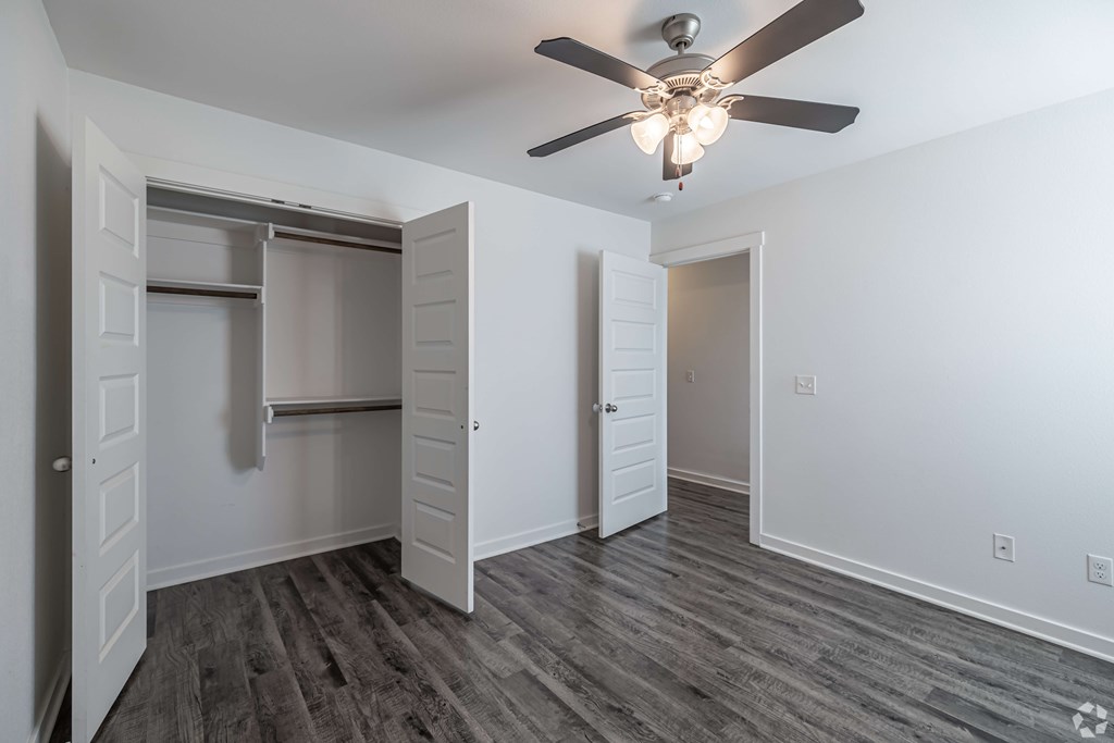 A room with a ceiling fan and a closet with a sliding door.