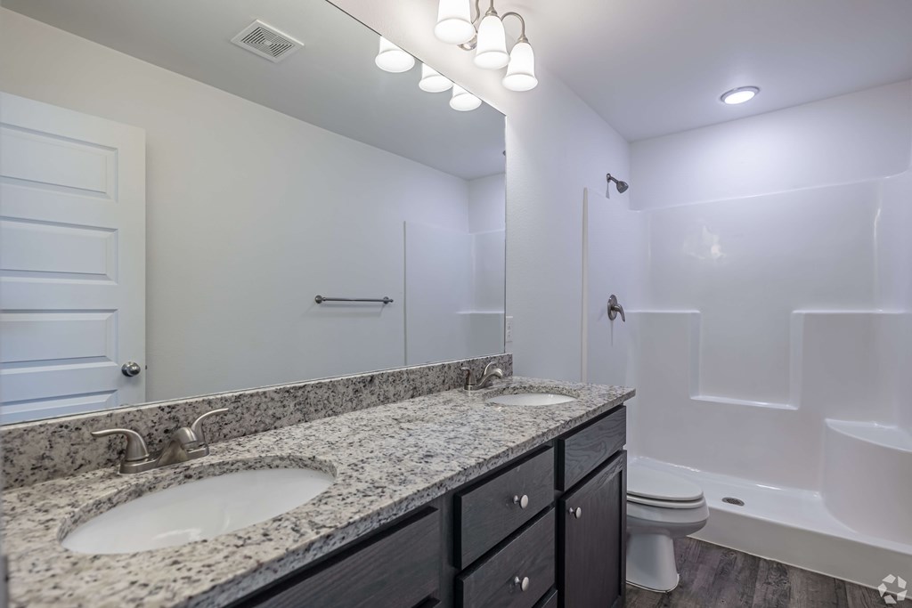 A bathroom with a marble countertop and a white tub.
