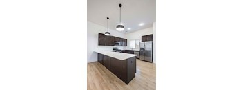 A modern kitchen with dark brown cabinets and a white countertop.