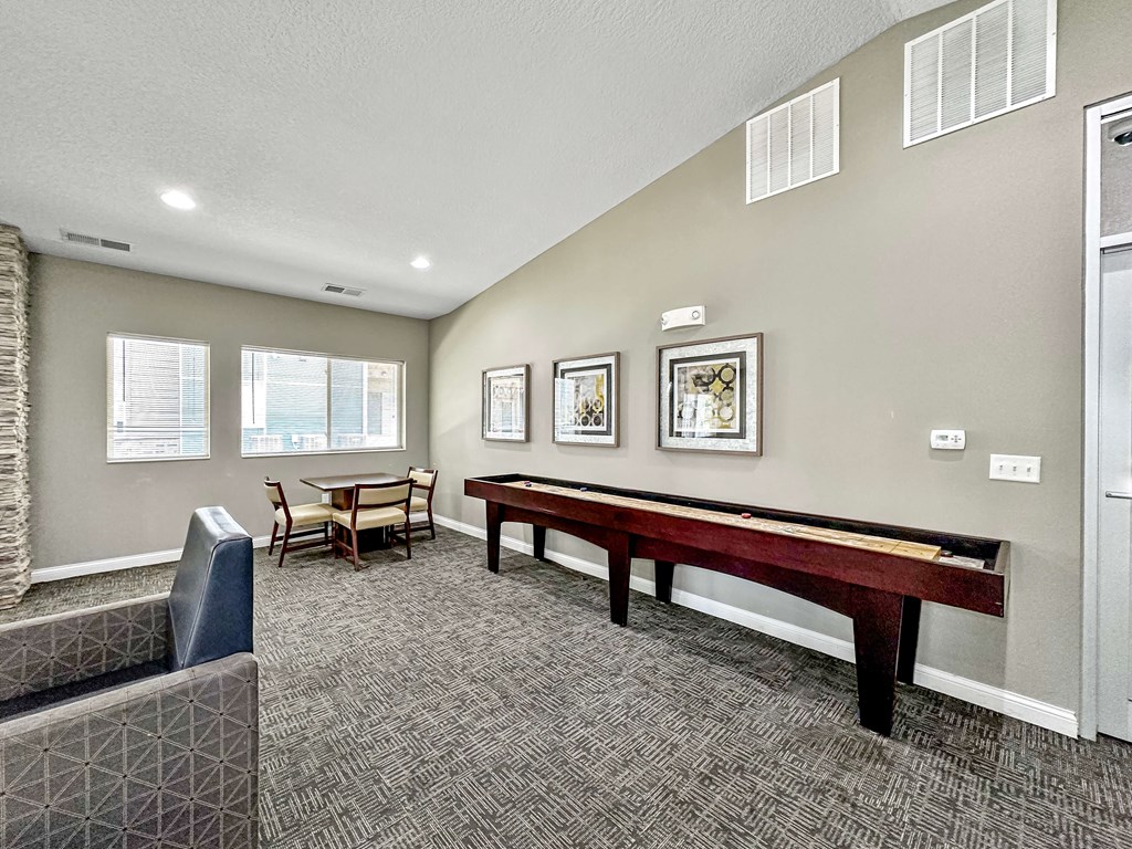 A room with a pool table, chairs, and pictures on the wall.