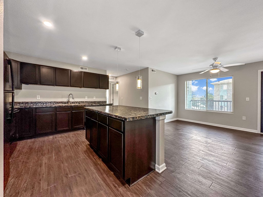 A kitchen with dark wood cabinets and a marble countertop.