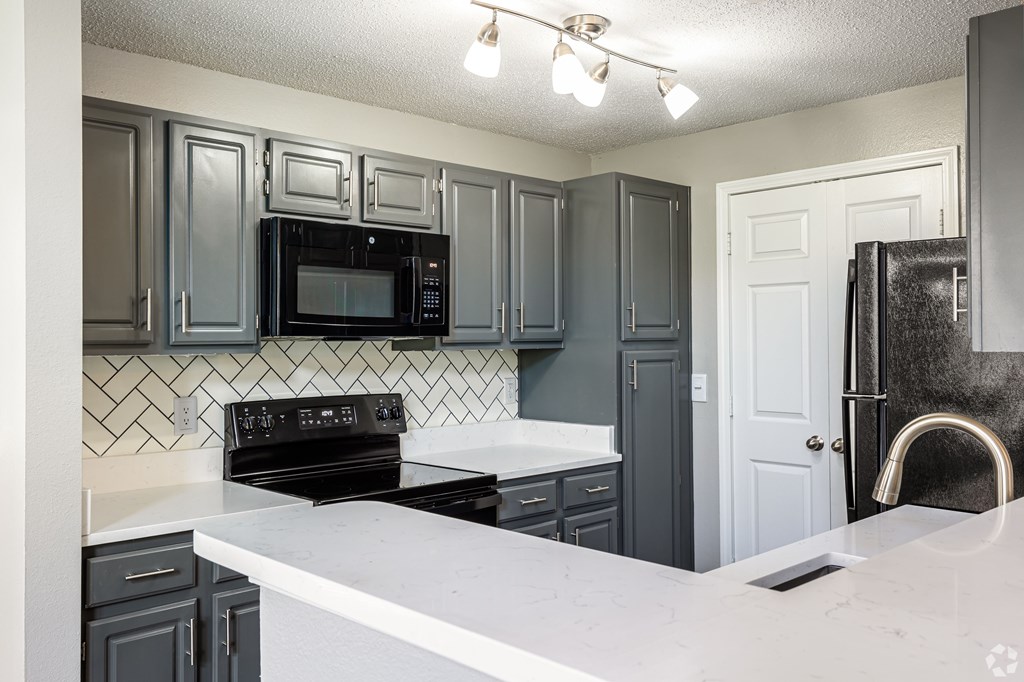 A kitchen with black cabinets and a white counter.
