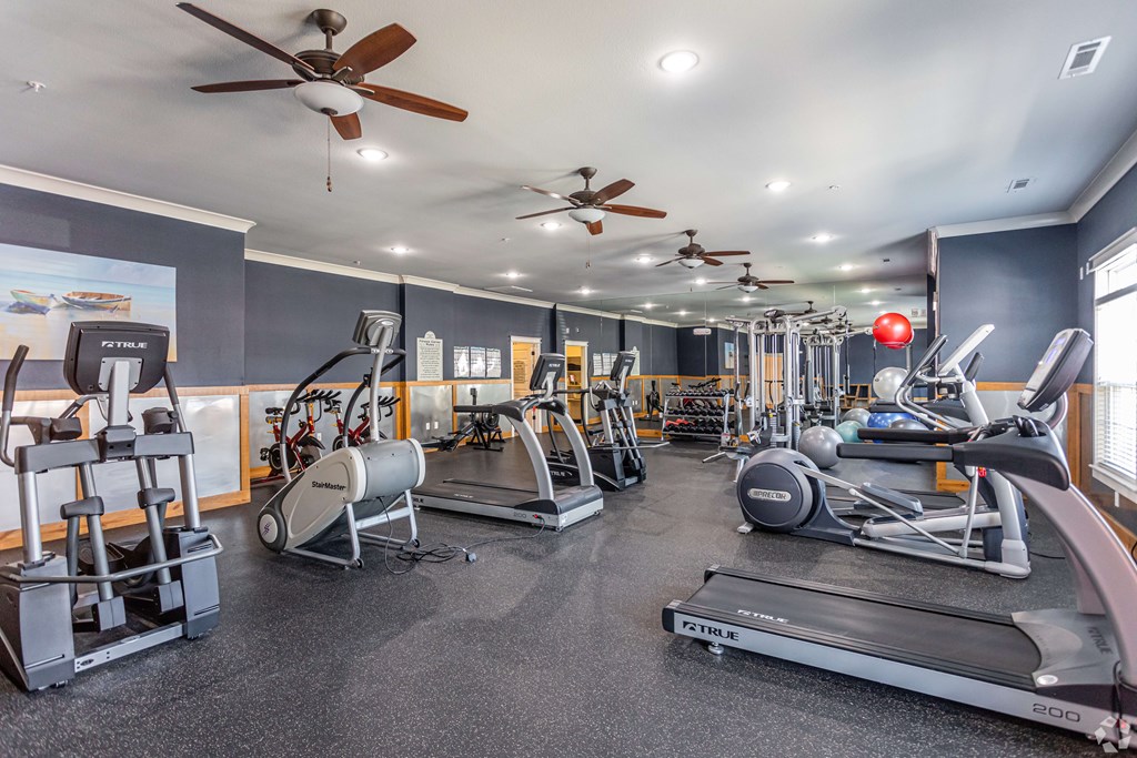 a gym with weights and cardio equipment and ceiling fans