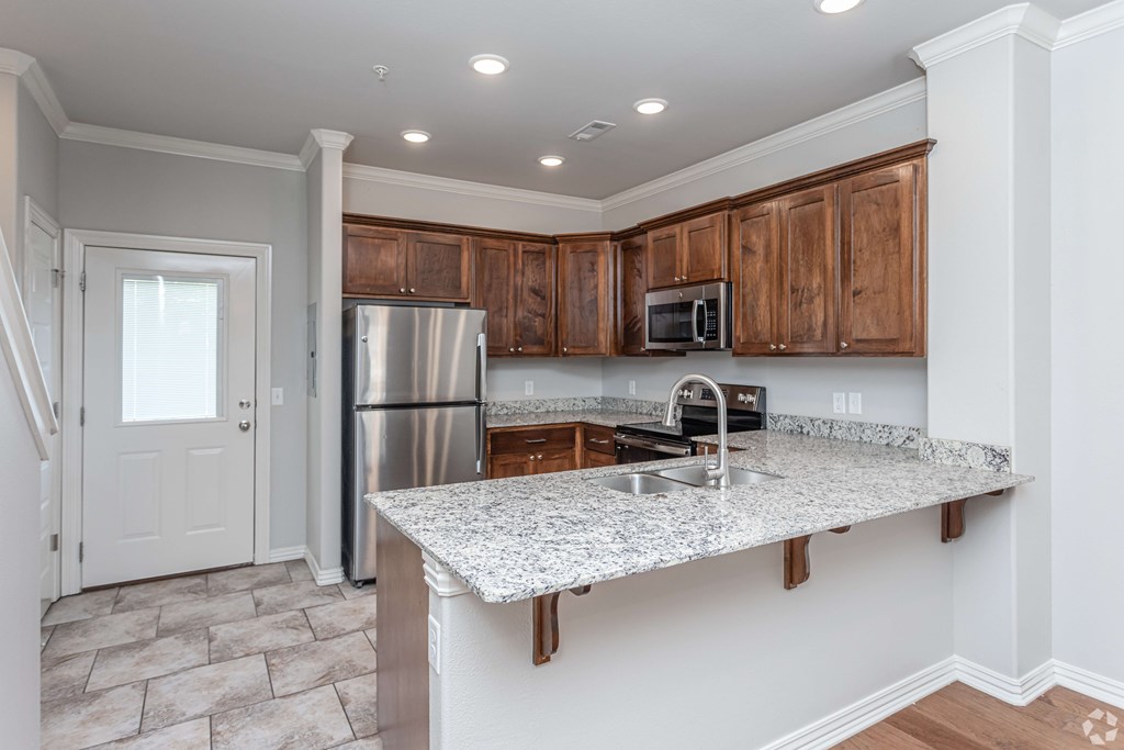 a kitchen with a granite counter top and a stainless steel refrigerator