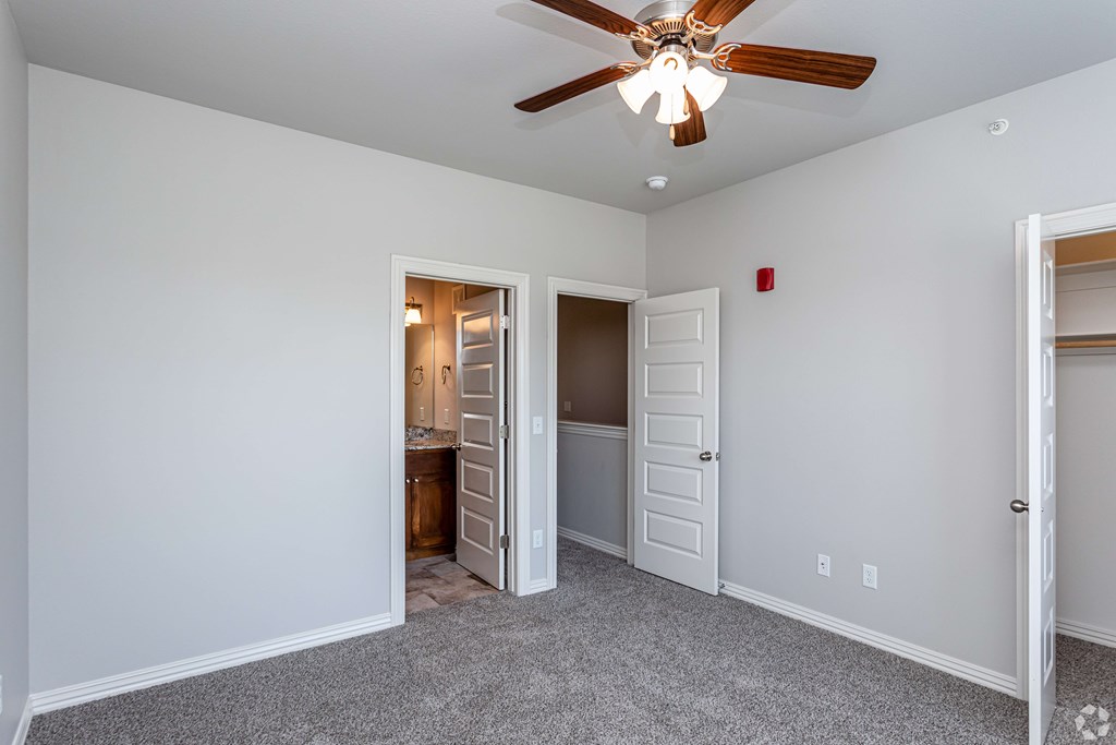 a bedroom with a ceiling fan and a door to a bathroom