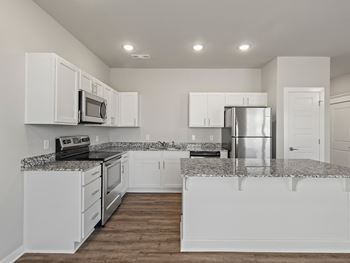 an empty kitchen with white cabinets and granite counter tops at Hillcrest Village, Springdale, 72762