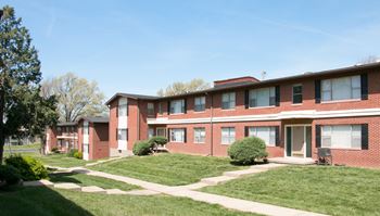 A red brick apartment building with green lawns in front.