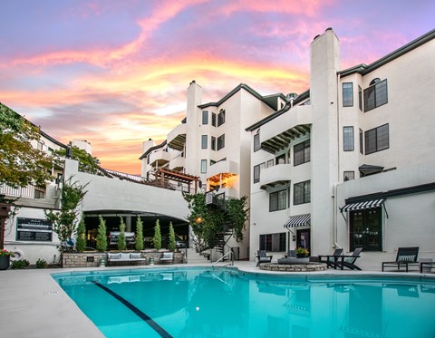 A large white building with a pool in front of it.